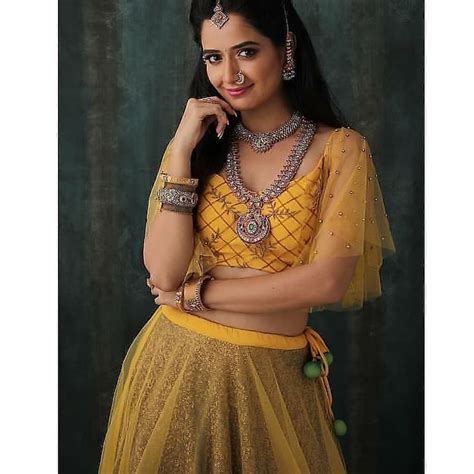 A Woman In A Yellow And Gold Lehenga Posing For The Camera With Her