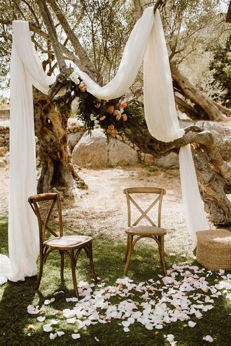 An Outdoor Ceremony With White Draping And Flowers On The Grass Two