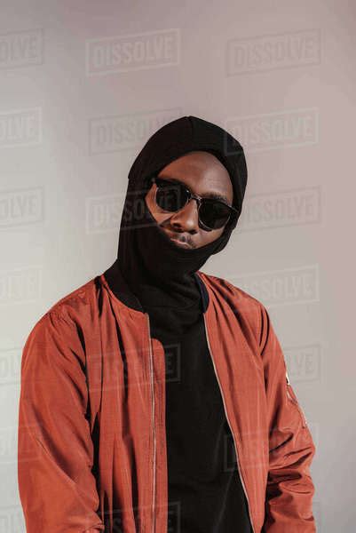 Stylish Young African American Man Wearing Hood With Face Mask Isolated On Light Background