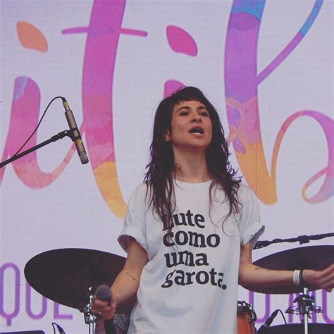 A Woman With Long Hair Standing In Front Of A Microphone And Drum Set