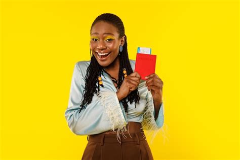 Premium Photo Joyful African Lady Holding Passport And Tickets On Yellow Background