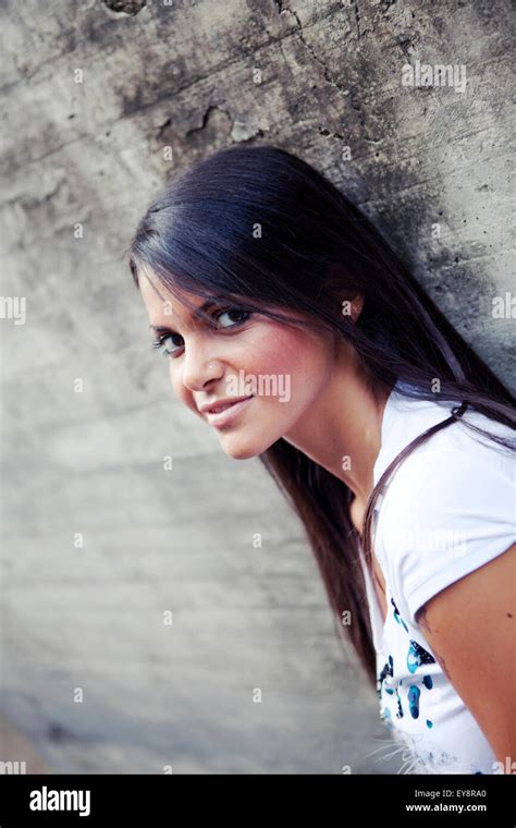 Diagonal Portrait Of A Brunette Girl Leaning Against A Concrete Wall