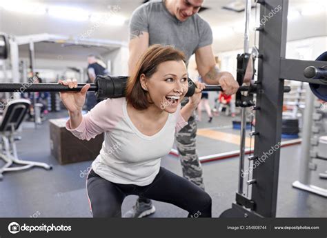 Middle-aged woman doing sports exercise in fitness center. Personal gym ...