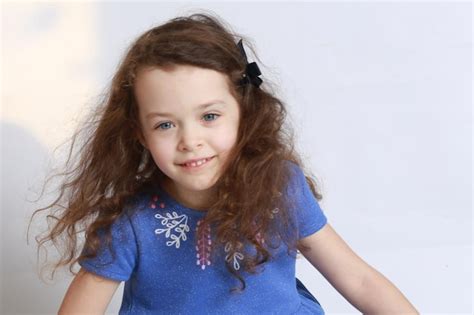 Premium Photo Portrait Of Girl Smiling While Sitting Against White