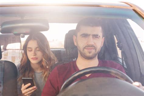 Front View Of Unshaven Male Driver Sits At Wheel And Drives His