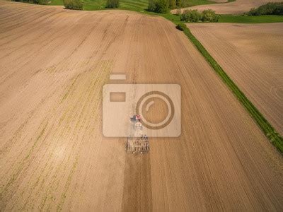 Z lotu ptaka ciągnik z przyczepą w pracy w polu złotego pszenicy