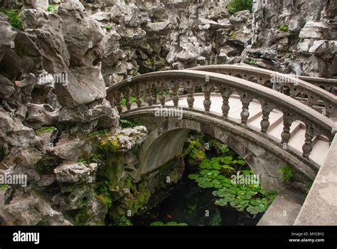 Ancient Stone Arch Bridge Over Pond Inside Chinese Rock Garden Stock