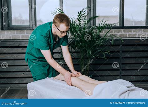 A Male Massage Therapist Massages The Feet And Legs Of Female Legs