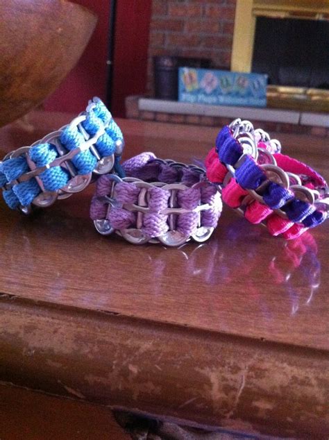 Three Bracelets Sitting On Top Of A Table Next To A Vase And Fire Place