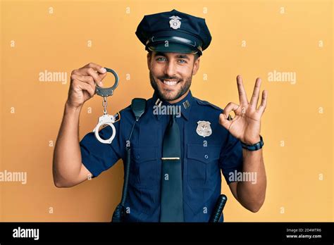 Handsome Hispanic Man Wearing Police Uniform Holding Metal Handcuffs