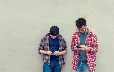 Dos Amigos Adolescentes En Una Pared Revisando Sus Tel Fonos Celulares