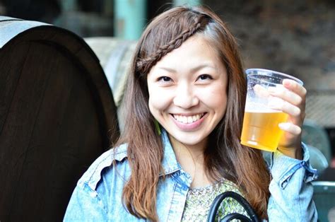 Premium Photo Smiling Young Woman Holding Beer Glass Against Barrels