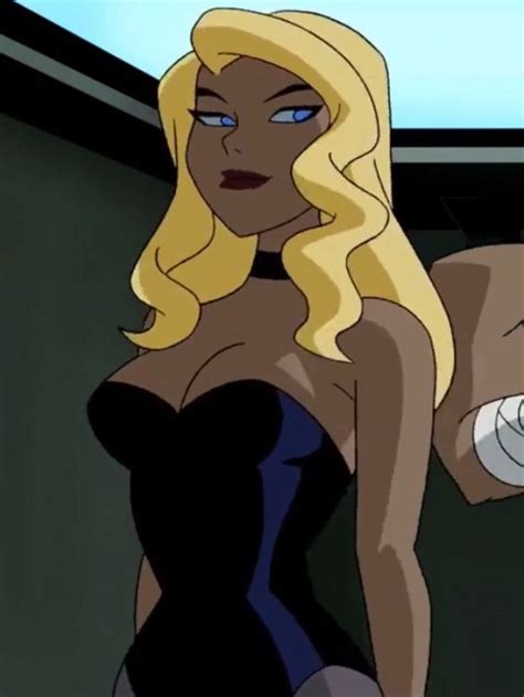 A Woman With Blonde Hair And Blue Eyes In A Black Dress Holding A White