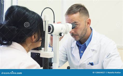 El Oftalmólogo Atento Examina Los Ojos De Su Paciente Imagen De Archivo