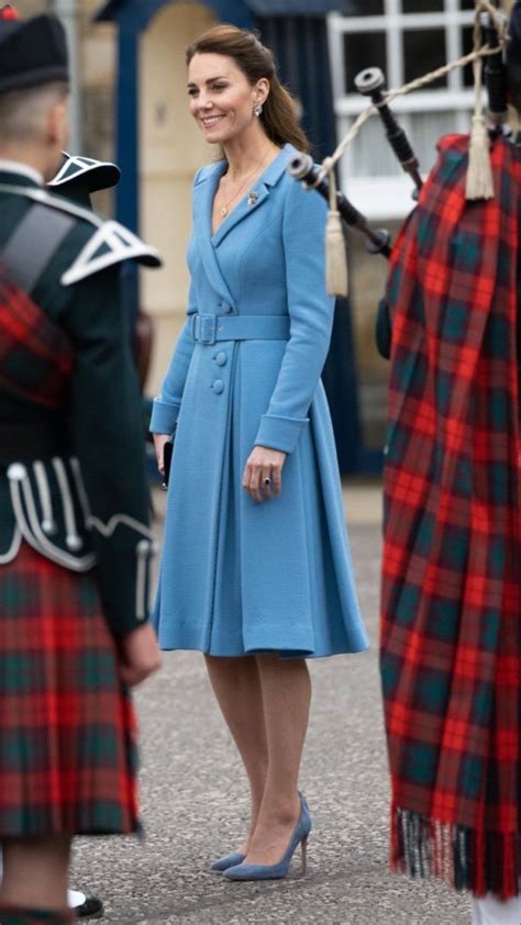 A Woman In A Blue Coat And Plaid Dress Standing Next To Some Men In Kilts