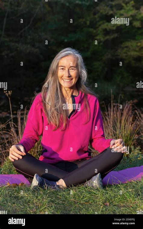 Happy Mature Woman Sitting On Grass Stock Photo Alamy