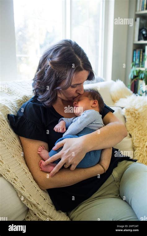 Loving Mother Kisses Her Son On The Forehead While At Home Stock Photo