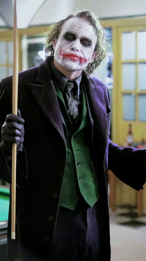 A Man Dressed As The Joker Holding A Pool Stick