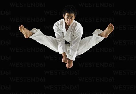 Asian Male Karate Black Belt Kicking In Air Stock Photo