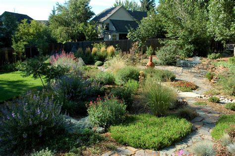 A Garden With Lots Of Different Plants And Rocks In The Grass Along