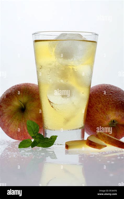 A Glass Of Apple Juice With Ice Cubes And Apples On The Side Stock