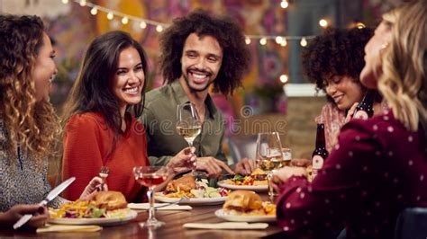 Multi Cultural Group Of Friends Enjoying Night Out Eating Meal And