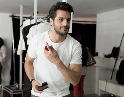 A Man In A White T Shirt Holding A Cell Phone