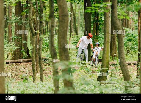 Selective Focus Of Father And Son In Helmets Riding Bicycles In Forest