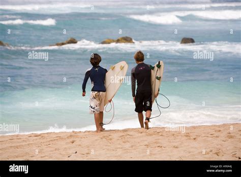 Two Surfers Look At The Waves On A North Shore Beach Oahu Hawaii