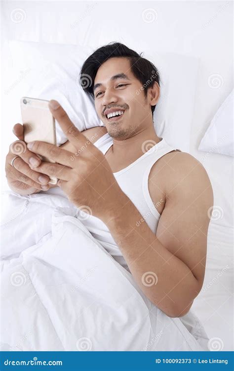 Handsome Asian Man Using A Cellphone While Lying Down Stock Image Image Of Adult Bedroom