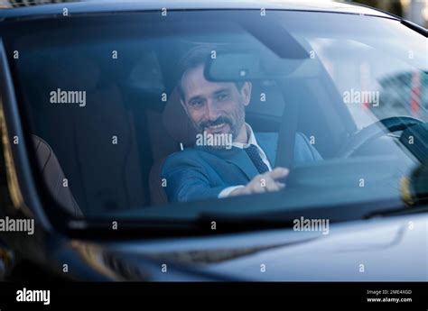 Smiling Mature Businessman Checking GPS Seen Through Windshield Of Car