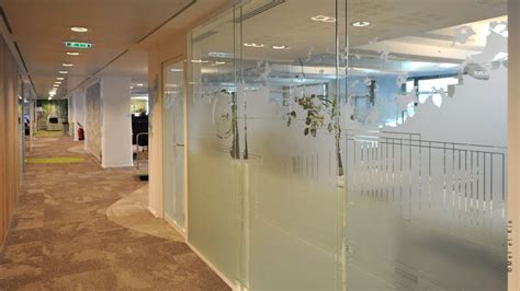 An Office Hallway With Glass Partitions And Plants Hanging On The Wall