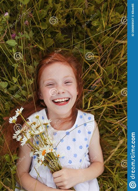 A Red Haired Girl Lies On The Grass With A Bouquet Of Daisies In Her