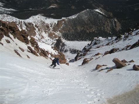 A Man Riding Skis Down The Side Of A Snow Covered Slope On Top Of A