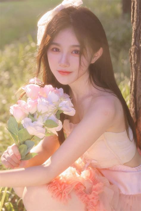 A Woman In A White Dress Holding Pink And White Flowers Sitting On The