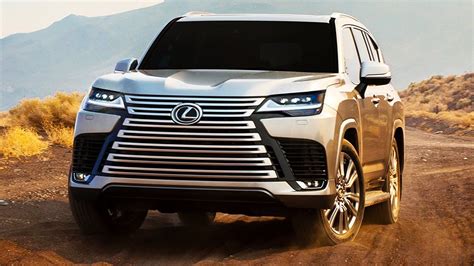 The Front End Of A Silver Suv Driving Down A Dirt Road With Mountains