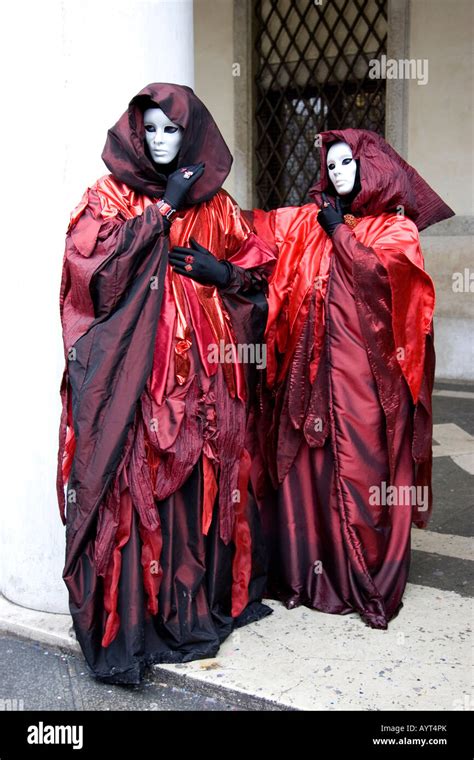 Two People Wearing Red And Black Costumes Hooded Cloaks And Masks