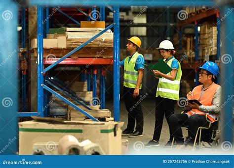 Male Manager In Wheelchair And Young Storehouse Employees Inspecting