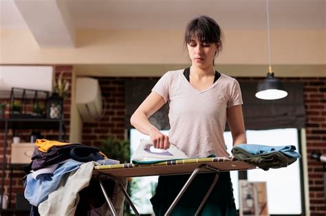 Mujer moderna haciendo tareas domésticas planchando ropa con vapor