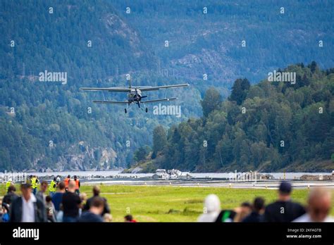 A vintage double-decker airplane landing with spectators at runway ...