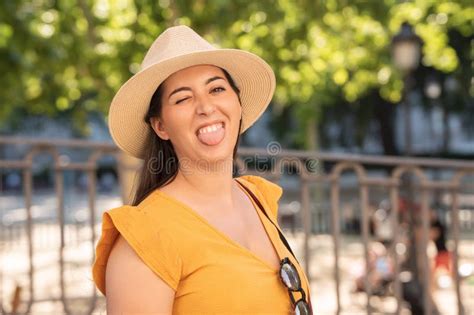 Woman In Sunhat Winking And Sticking Tongue Out Playfully Outdoors