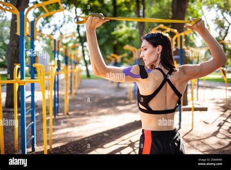 Brunette Muscular Woman Posing With Fitness Resistance Band In Park