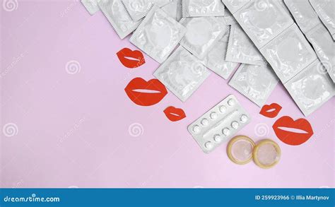 Many White Packages Of Unopened Condoms With Paper Kisses On A Pink