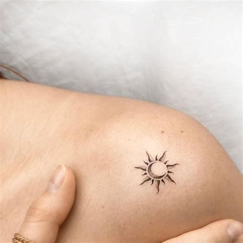 A Woman With A Small Tattoo On Her Shoulder And Arm Holding The Sun In