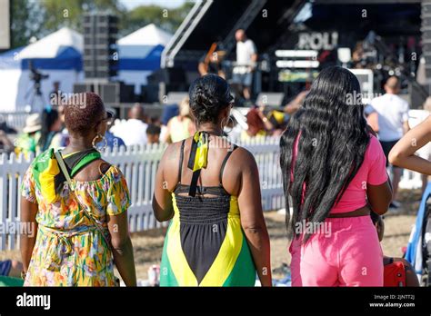 Three women at the East Beach Festival, one in a Jamaican flag dress ...