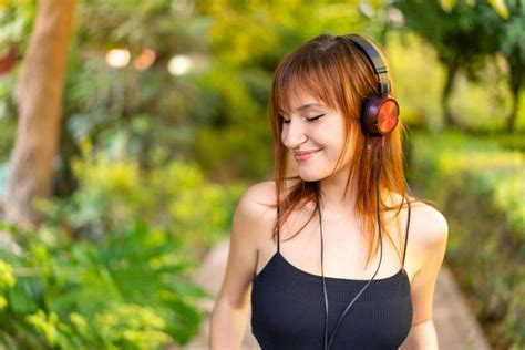 Premium Photo Young Pretty Redhead Woman At Outdoors Listening Music