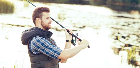 Fisherman With A Spinning And Bait Catching Fish On A Lake Or River