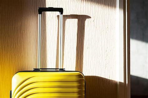 Premium Photo | Yellow suitcase by the wall