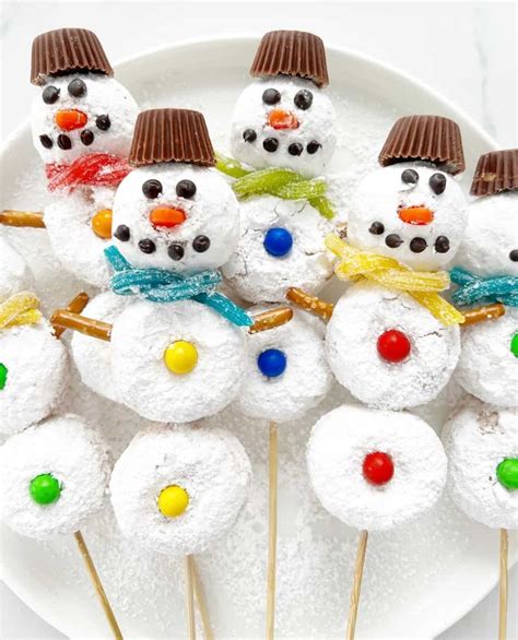 Snowmen Made Out Of Marshmallows On A White Plate With Chocolate Sticks