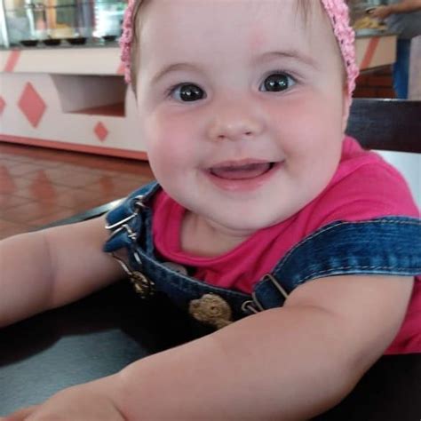 A Smiling Baby Girl Sitting At A Table